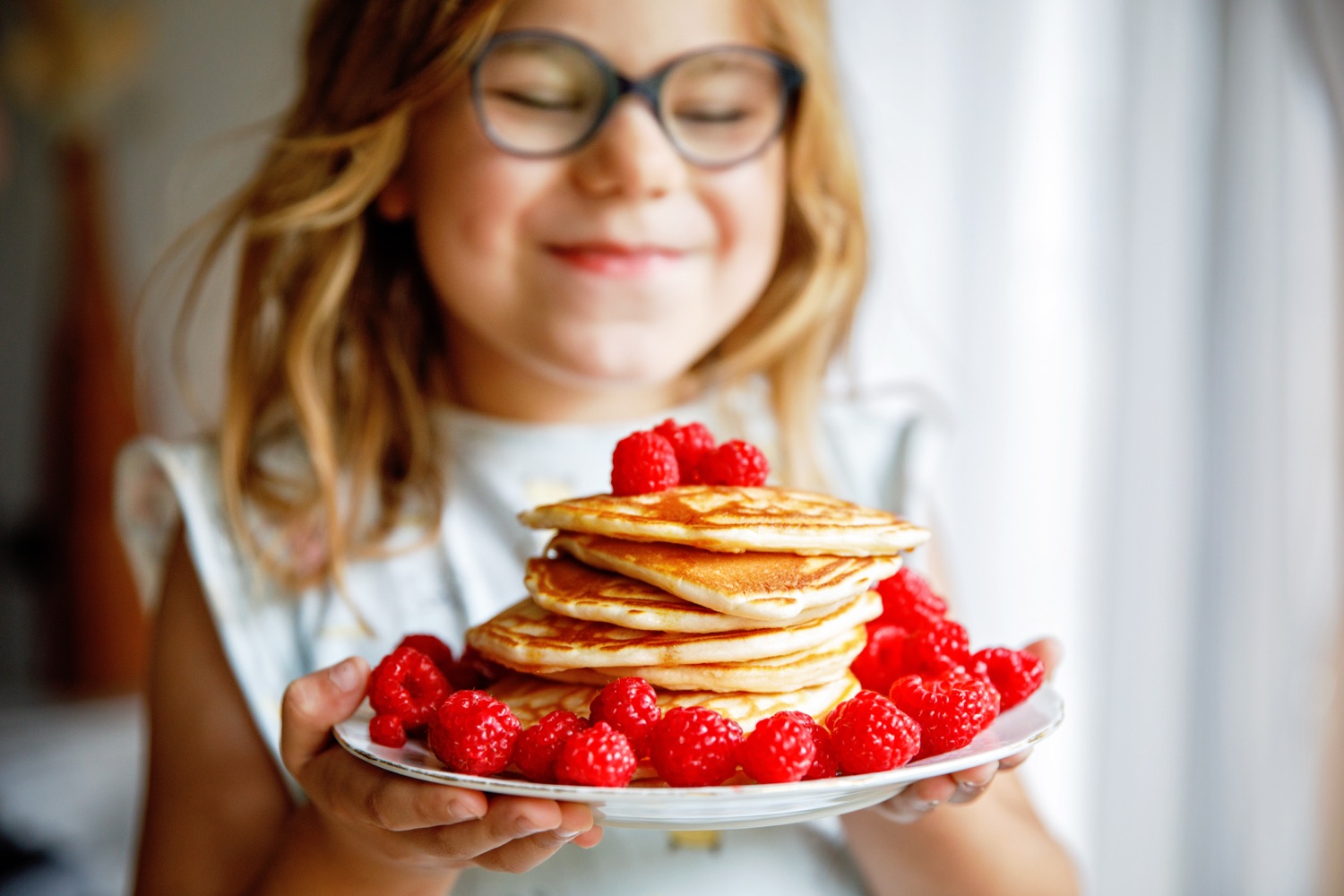 Young child happily eating a plate of food